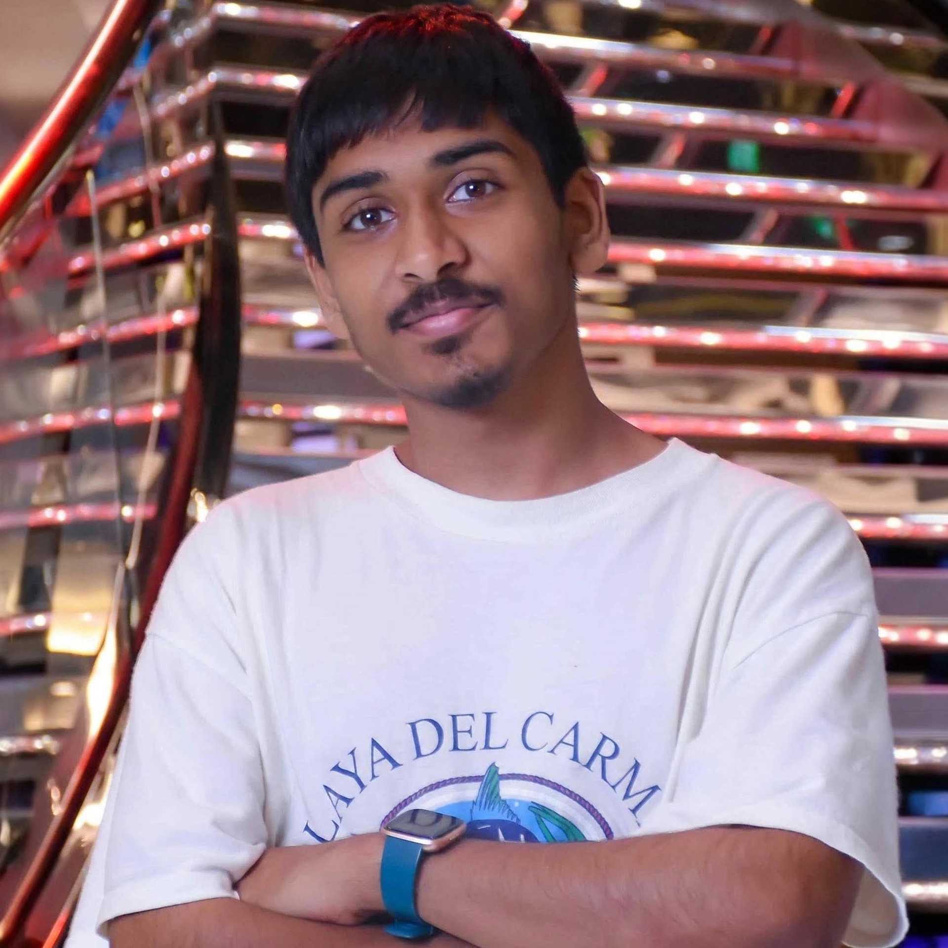 A young brown man with black hair appears wearing a t-shirt in an indoor setting.